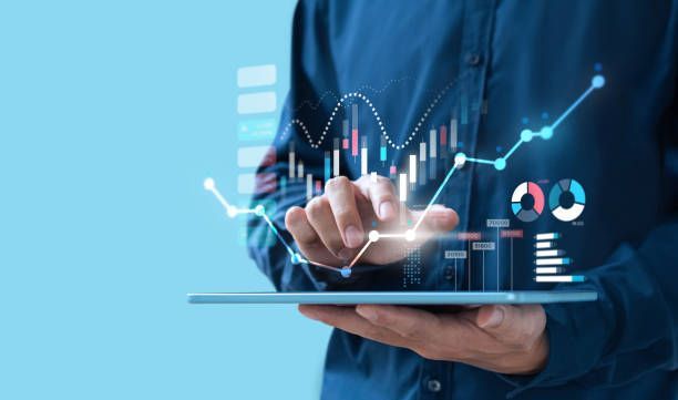 Business professional analyzing digital financial data on a tablet with futuristic charts and graphs, symbolizing investments in artificial intelligence and robotics in U.S. stock markets.