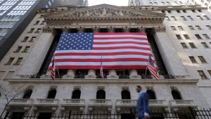 The New York Stock Exchange building with a giant American flag covering its facade, symbolizing financial security and stability often associated with U.S. Treasury Bonds.