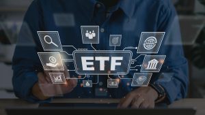 A person in a dark blue shirt interacts with a digital interface displaying the word “ETF” at the center, surrounded by icons representing finance, technology, and global markets, symbolizing how Thematic ETFs are transforming modern investment portfolios.