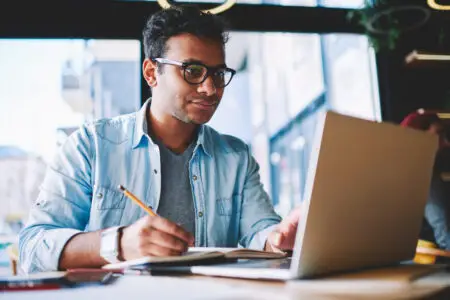 Person taking online classes and writing notes